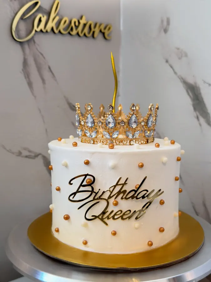 Weiße Torte mit goldenen Perlen, Schriftzug und funkelnder Krone